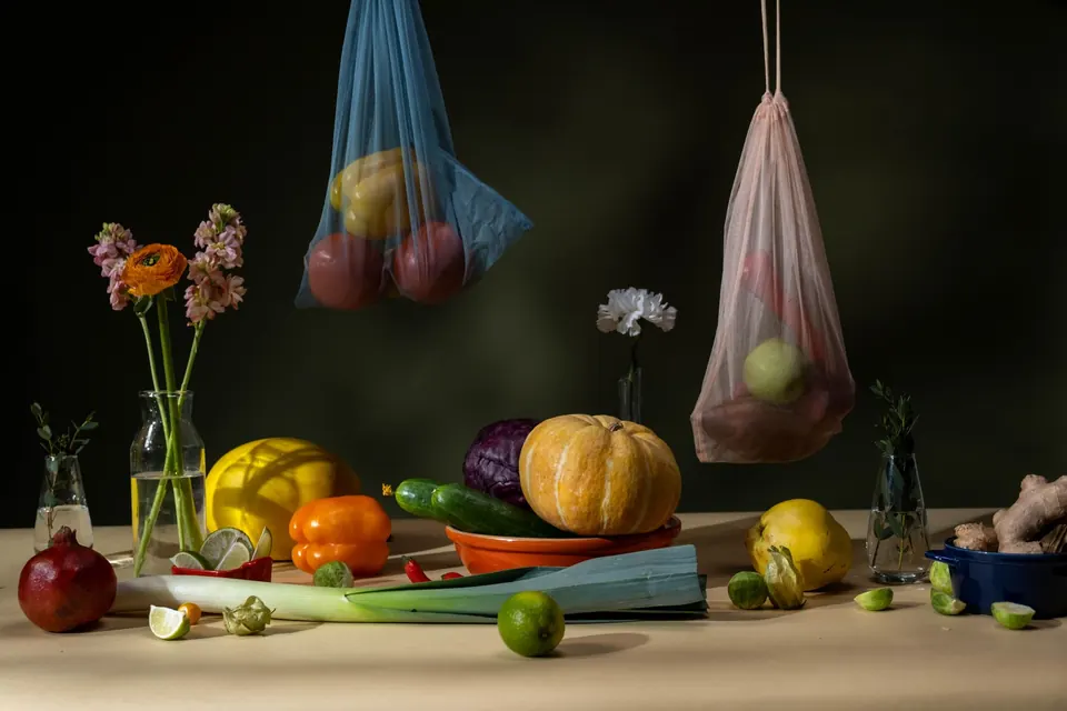 Still life of seasonal vegetables and flowers against a dark backdrop